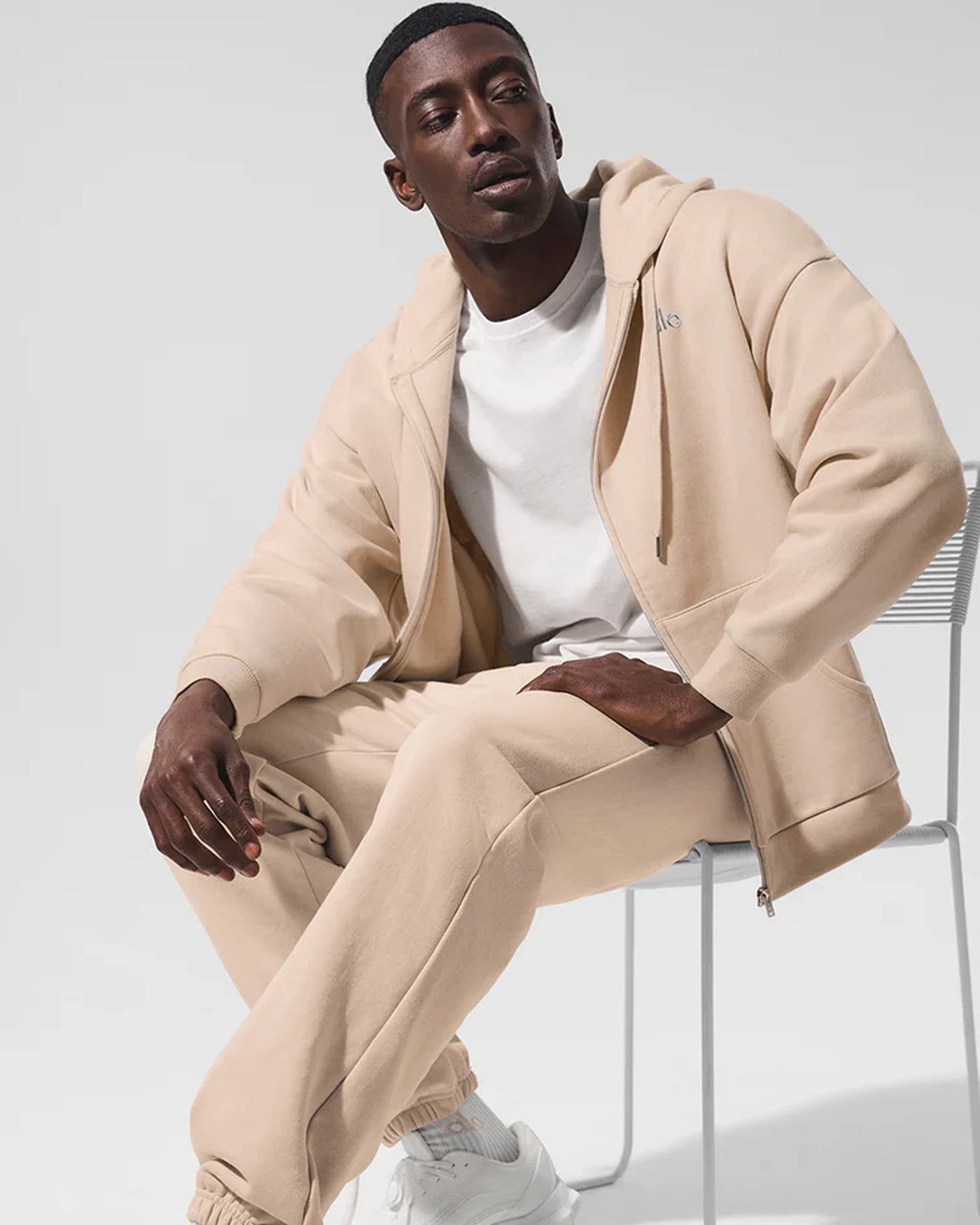 Alo-Accolade-Full-Zip-Hoodie-Men-Sitting-On-Chair