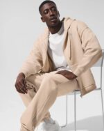 Alo-Accolade-Full-Zip-Hoodie-Men-Sitting-On-Chair